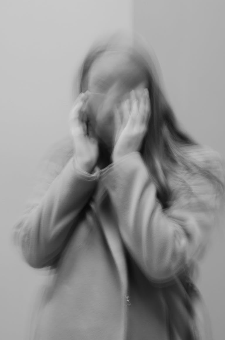 A blurred black and white portrait of a woman in motion, creating an abstract effect.