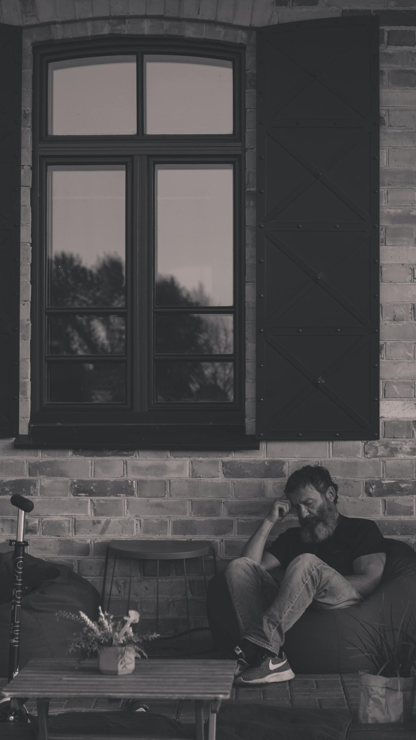 Black and white photo of a man sitting by a window, reflecting a calm, moody atmosphere.